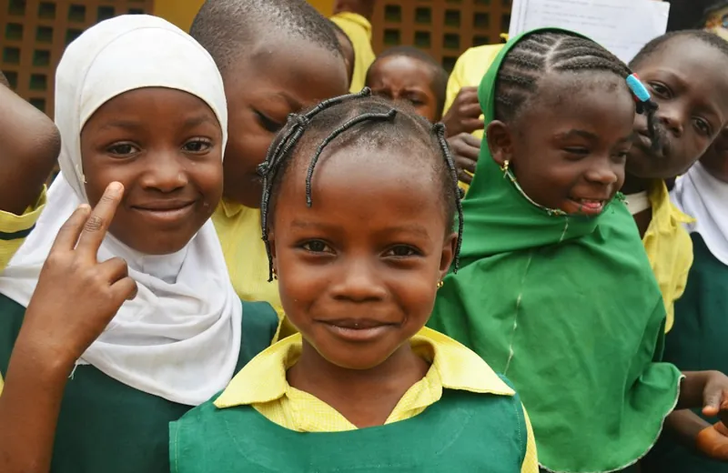 Smiling pupils in green and yellow school uniforms